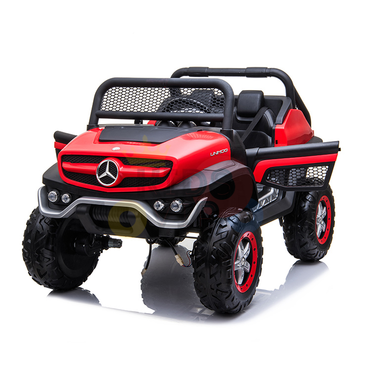 The Red 12V/4X4 Official Mercedes Unimog Junior Ride On UTV is a realistic mini SUV toy with a steering wheel, two seats, large black tires with red rims, an off-road design featuring a prominent front grille and round headlights. It includes remote control functionality.