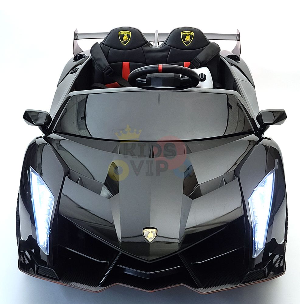 A Black 2X12V Limited Edition 4WD Lamborghini Veneno Ride on Car, RC showcases sharp angular headlights, a glossy finish, red and black seats, and a steering wheel. The Kids VIP car features the Lamborghini logo and sits against a white backdrop.