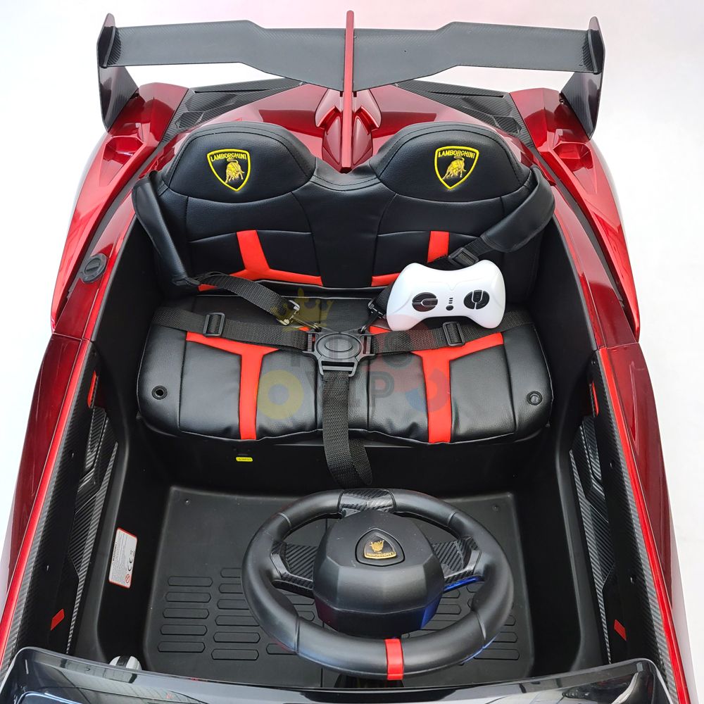 Overhead view of a Red 2X12V Limited Edition 4WD Lamborghini Veneno Ride on Car interior, featuring black and red detailing. Includes a steering wheel with emblem, seat with safety harness, and parental remote control on the passenger seat.