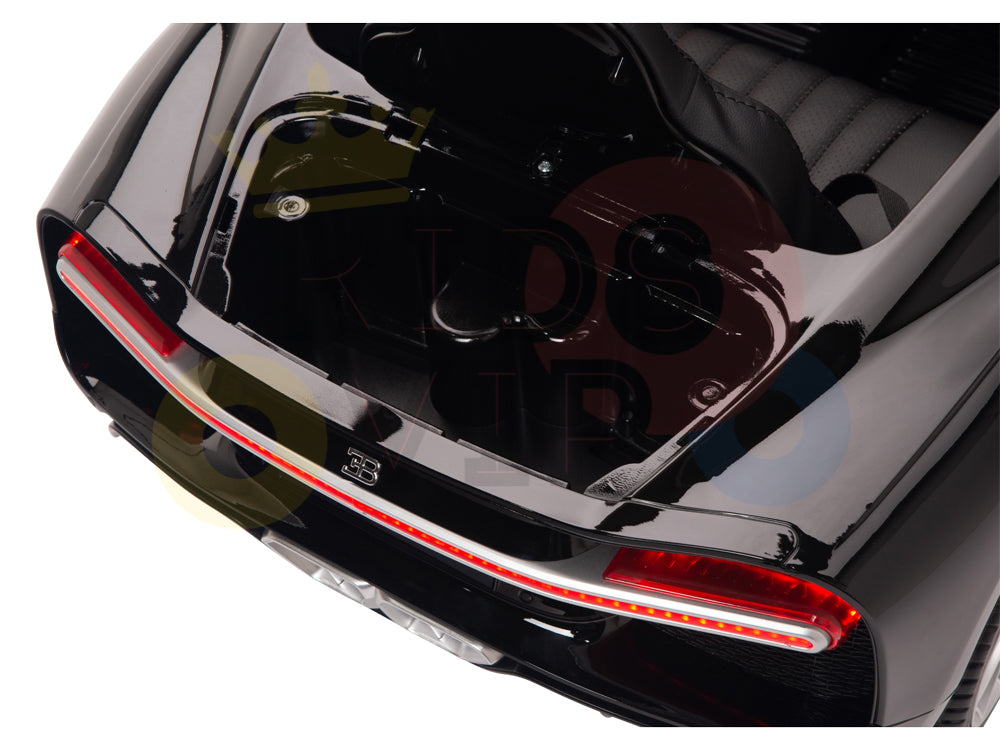 A close-up of the rear end of a red 12V Bugatti Chiron kids ride-on car shows a red LED tail light strip. The open trunk reveals a sleek black interior, and theres a subtle reflection on the shiny surface. This remote control model features durable Eva rubber wheels.
