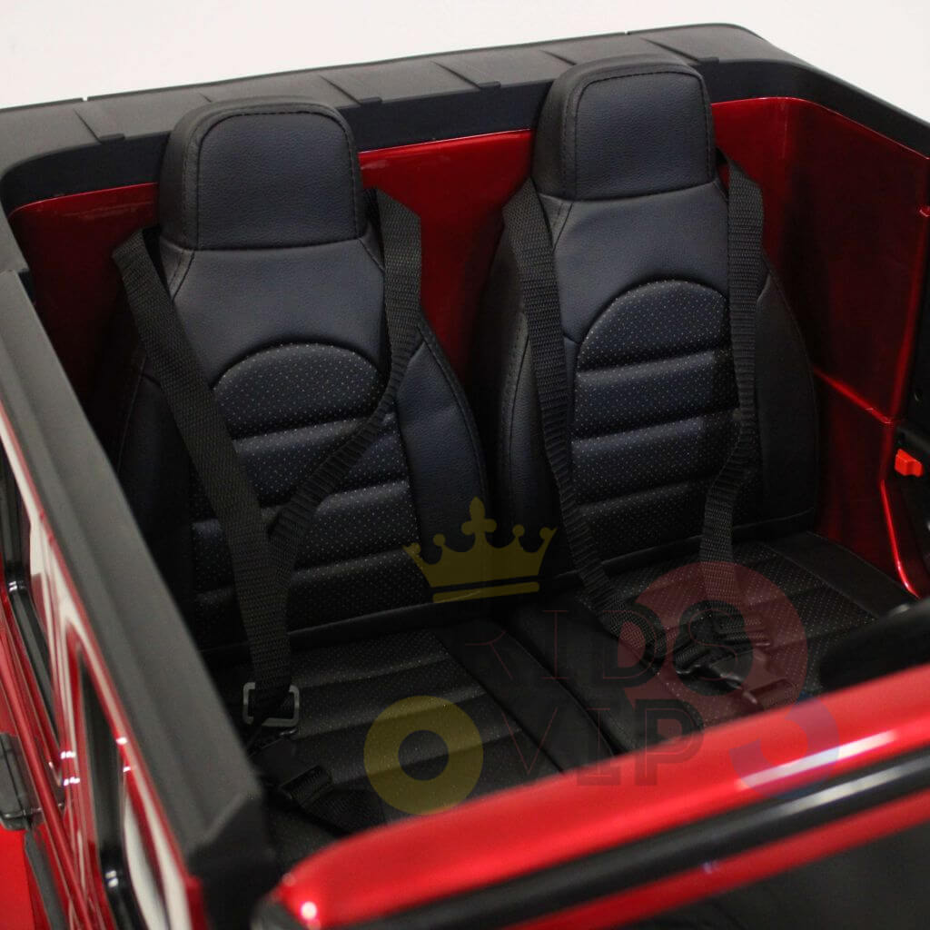 Inside the red Special LED Edition 24V Mercedes G Series Ride On, two black sporty car seats with seatbelts are positioned in the open rear, delivering an authentic and thrilling experience for young drivers.