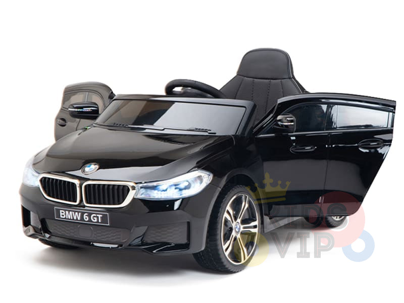 The Black Licensed BMW GT 12V Kids Ride On Power Car features upgraded chrome accents and detailed headlights. The model, styled with an open drivers side door, visible steering wheel, and seat, is set against a white background.