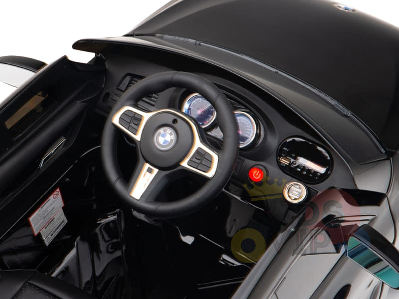 Interior view of the Black Licensed BMW GT 12V Kids Ride On Power Car with Remote Control featuring a BMW-style steering wheel, dashboard with dials and controls. The shiny surface showcases its upgraded features, including the official electric kids ride on BMW logo on the floor.
