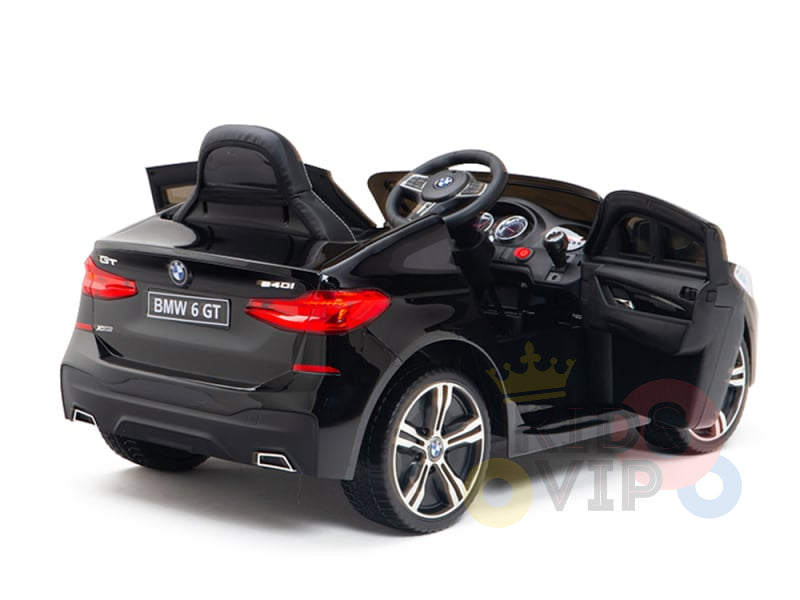 The Black Licensed BMW GT 12V Kids Ride-On Power Car with Remote Control features open doors, a steering wheel, branded detailing at the back, a detailed dashboard, shiny wheels on the side, and upgraded features.