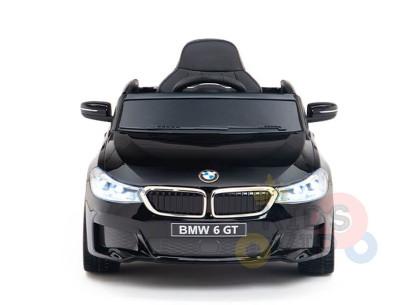 A small, black BMW GT toy car is shown from the front, featuring an upgraded detailed grille and headlights with a single seat. This official electric kids ride-on proudly displays the BMW 6 GT label and is named the Black Licensed BMW GT 12V Kids Ride On Power Car with Remote Control.