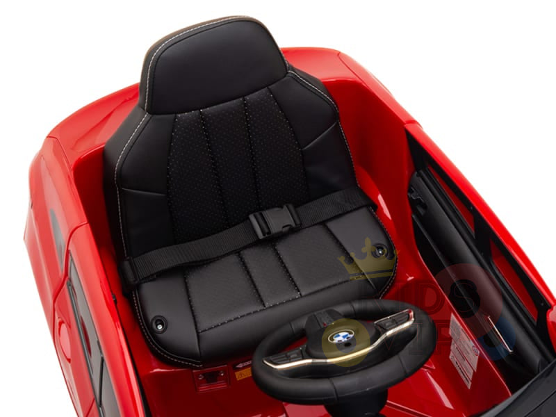The Red 12V BMW GT Kids Licensed Ride-On Car features a black leather seat, seatbelt, logo-adorned steering wheel, sleek design, and a winding mechanism by the seat. Its streamlined dashboard offers an authentic driving experience. Rubber wheels and remote control enhance its functionality.