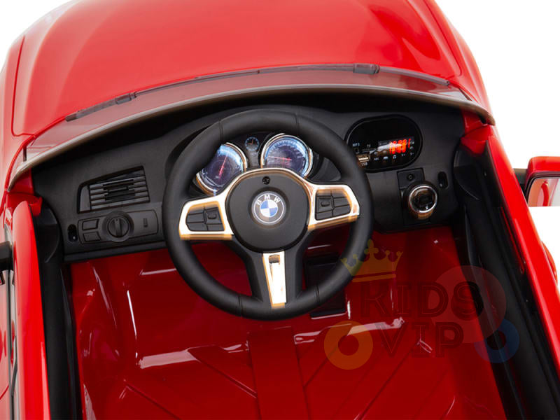 The top view of the Red 12V BMW GT Kids Licensed Ride-On Car reveals a dashboard with a BMW-logo steering wheel. It features detailed dials and buttons, mimicking a real GT interior, while its glossy red flooring adds to the authenticity.