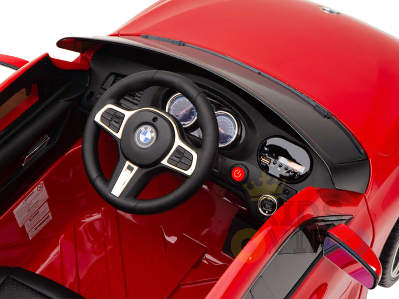 The Red 12V BMW GT Kids Licensed Ride-On Car features a red dashboard with gauges, a steering wheel with the BMW logo, and an electric power button. Its design mirrors the BMW GT with precise detail for miniature authenticity.