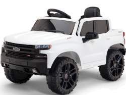 The White 12V Chevrolet Silverado Kids Licensed 1 Seater Ride-On Truck features oversized black wheels, a sleek design, a black interior with steering wheel, and the Chevrolet emblem on the grill. This stylish kids car offers remote control functionality and built-in music.