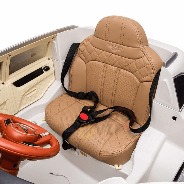 The White 12V Bentley Bentayga Ride-On Car for kids includes a brown leather seat, black harness straps, red steering wheel/dashboard, and beige interior accents. This licensed one-seater with rubber wheels also features remote control.