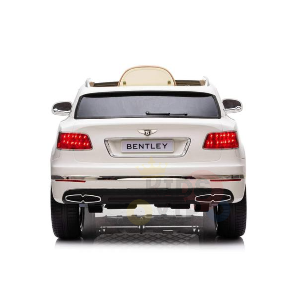 A rear view of the White 12V Bentley Bentayga Kids Licensed 1 Seater Ride On Car reveals illuminated red taillights, a beige seat, and realistic details like side mirrors and exhausts. Powered by a 12V setup, it features the iconic Bentley logo on its back.