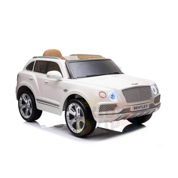The White 12V Bentley Bentayga Kids Licensed 1 Seater Ride On Car features a detailed grille, emblem, and headlights. It boasts large rubber wheels, a tan seat, and remote control capabilities, making it ideal for young adventurers.