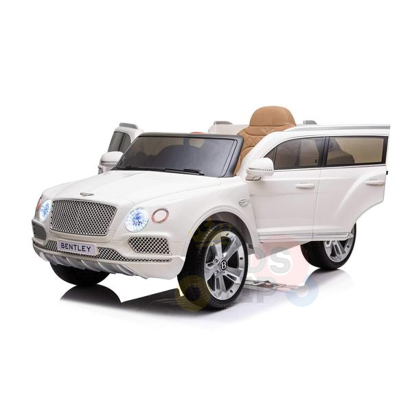 The White 12V Bentley Bentayga Kids Licensed Ride On Car boasts an open door, tan interior, realistic details, and features like headlights, logo, grille, and chrome wheels. It captures classic Bentley design in miniature with rubber wheels and a remote.