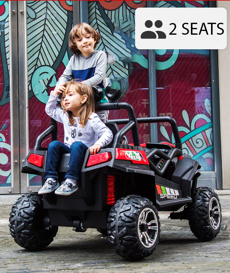 Two kids sit in a 4X4 Edition 24V Viper Kids Ride on Buggy, featuring large rubber wheels and red/green decals, parked on bricks. A sign reads 2 SEATS, with a colorful leaf-patterned mural backdrop adding to the adventure.