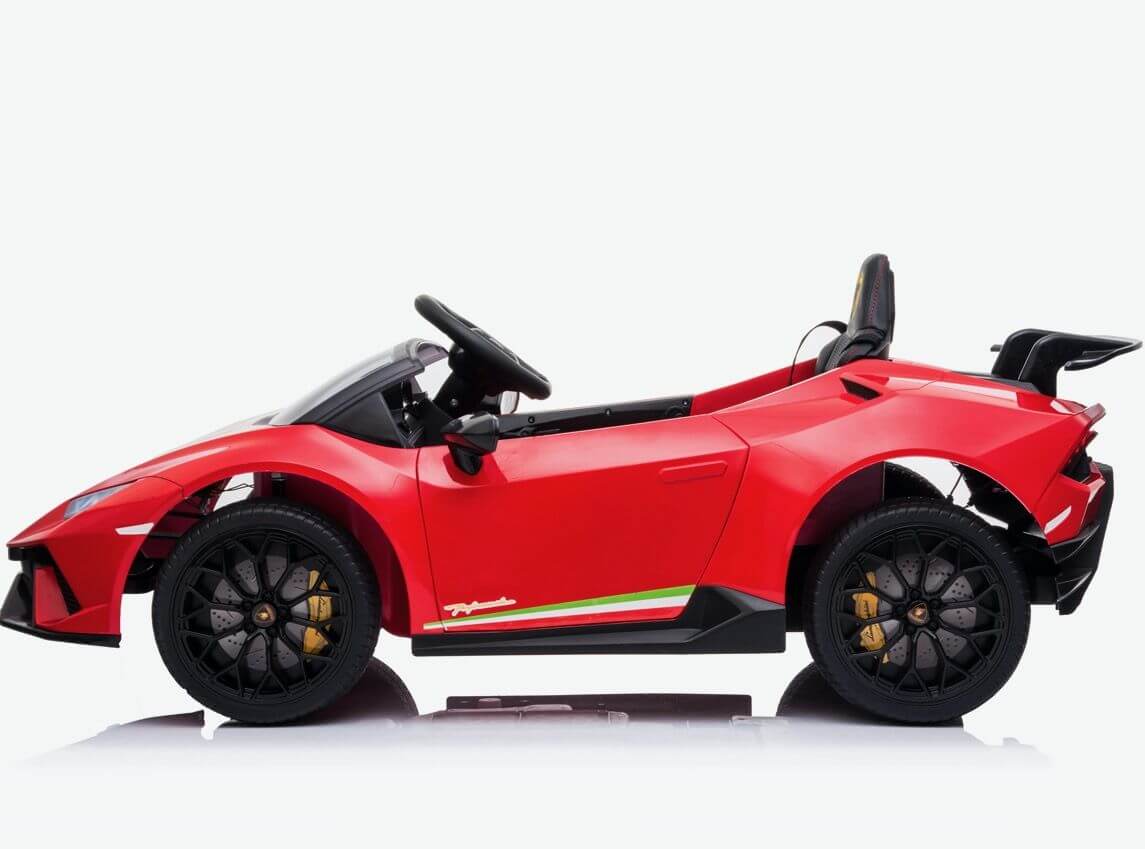 The Officially Licensed 12V Lamborghini Huracan Sports Edition Ride-on Car is shown in profile with black wheels, a steering wheel, and convertible style. It features a red body with sleek design and white and green side stripes against a plain background.