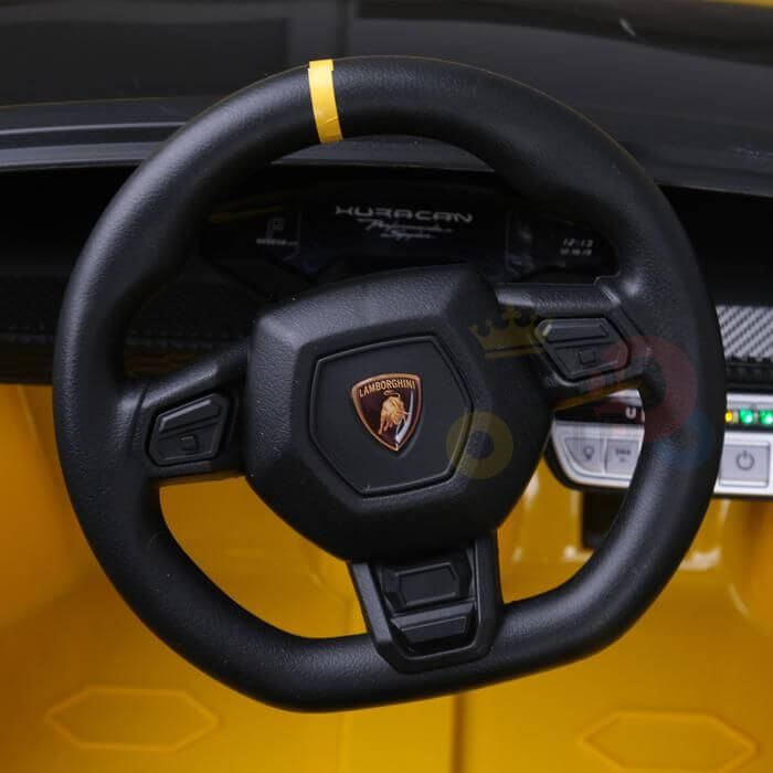 The Lamborghini Huracan Sports Edition ride-on car features a striking yellow interior, a steering wheel with the iconic logo and yellow stripe, and a dashboard proudly displaying Huracan, all enhancing the luxurious driving experience.
