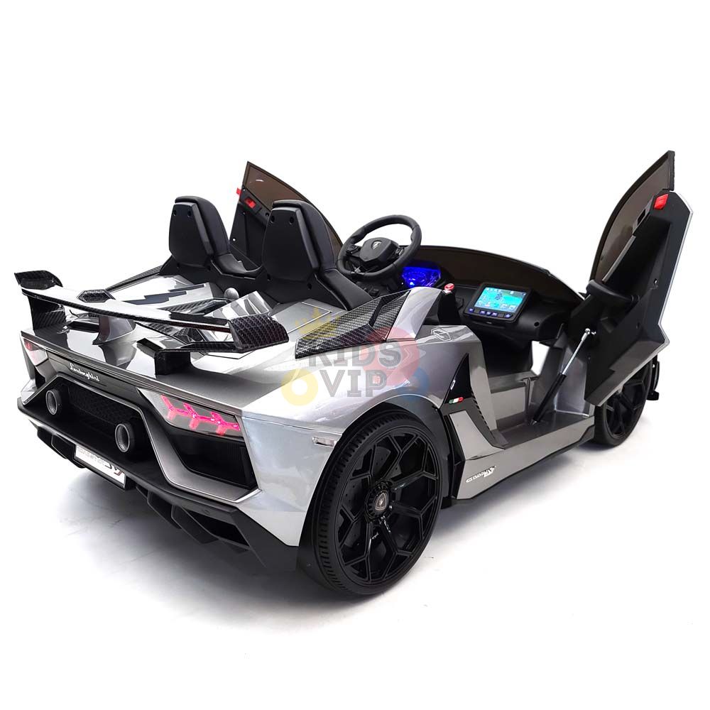 The Upgrade Your Ride: Experience the Thrill of Drifting with the Complete Edition 24V Lamborghini Sport Car features a sleek silver design with black accents, scissor doors, detailed dashboard with glowing elements, sporty black wheels viewed from a rear angle, and includes KidsVip Warranty.