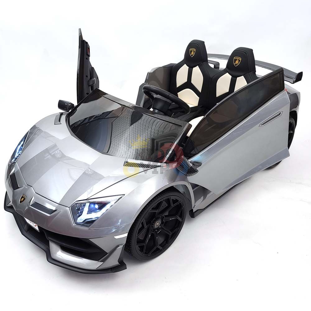 The Complete Edition 24V Lamborghini Sport Car in metallic gray, complete with a sleek design and open left door, features black wheels, dual seats, and a detailed steering wheel for an authentic sports car experience. Drive confidently with the KidsVip warranty.