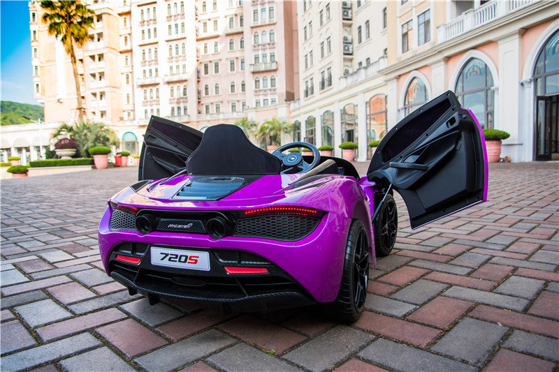 A Purple 12V McLaren 720S Kids Licensed Ride On Car with rubber wheels and remote, sits on a cobblestone path before a grand building with arched windows. With doors open and surrounded by potted plants, the 720S model is proudly displayed on its rear plate.