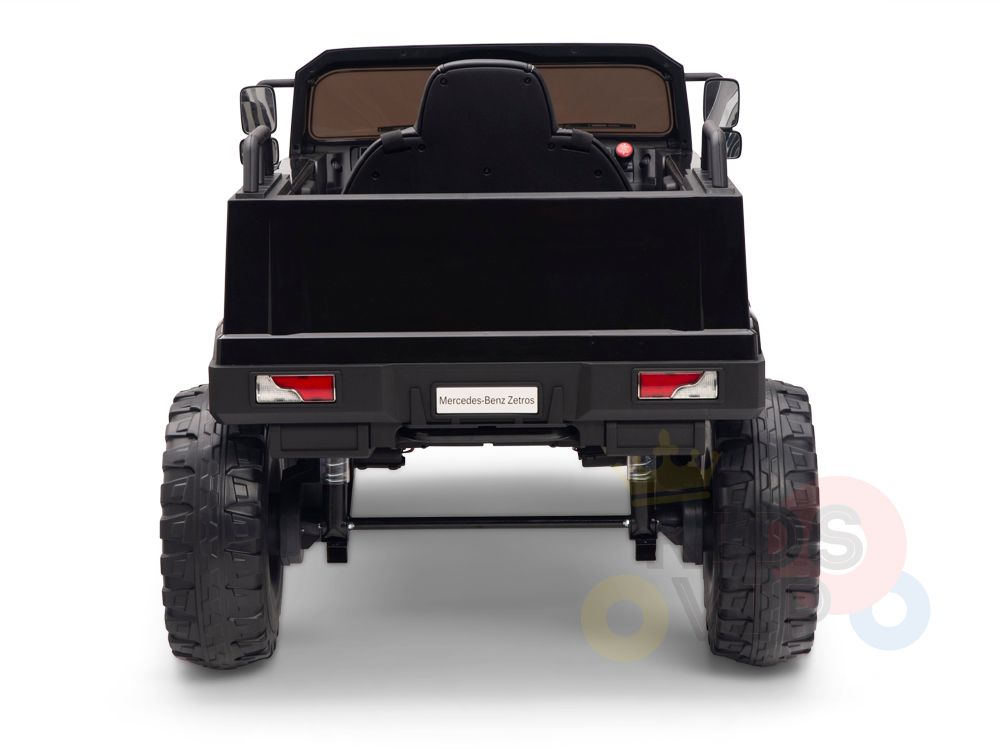 Rear view of a Black 12V Mercedes Benz Zetros Kids 1 Seater Ride On Truck with rubber wheels and Mercedes Benz Zetros license plate. Features include a steering wheel and seat, set against a crisp white background.