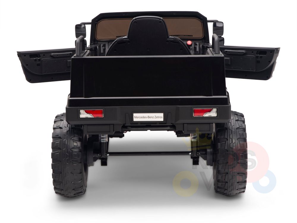A rear view of the Black 12V Mercedes Benz Zetros Kids 1 Seater Ride On Truck showcases its large rubber wheels and open cargo area. It features realistic detailing like taillights and visible axles, making it a standout ride for kids.