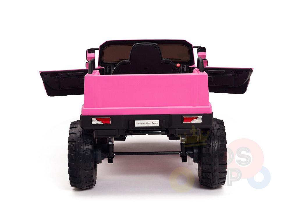 A pink 12V Mercedes Benz Zetros Kids Ride On Truck, with black accents, features open doors and rubber wheels. The interior includes a steering wheel and the Mercedes logo on the license plate, powered by a strong 12V12amp battery.