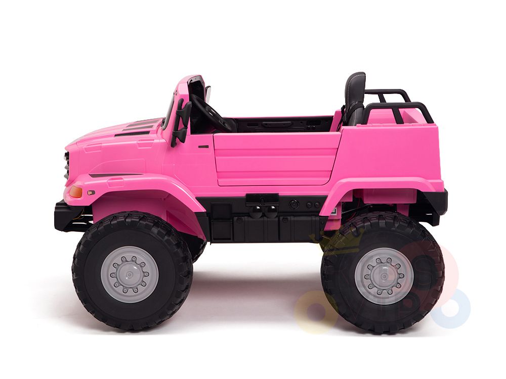 A side-view of the Pink 12V Mercedes Benz Zetros Kids 1 Seater Ride On Truck showcases its oversized black rubber wheels and open-top design. Powered by a robust battery, it features a small seat, steering wheel, and remote for endless fun.