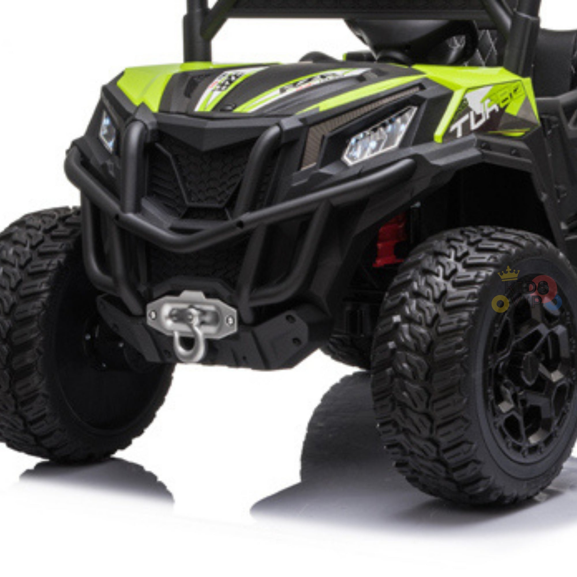 A close-up of the green Upgraded 12V Junior Sport Utility Ride On Buggy/UTV 4WD Edition w/Remote Control, featuring large black tires, rugged design, front winch hook, and detailed grille.
