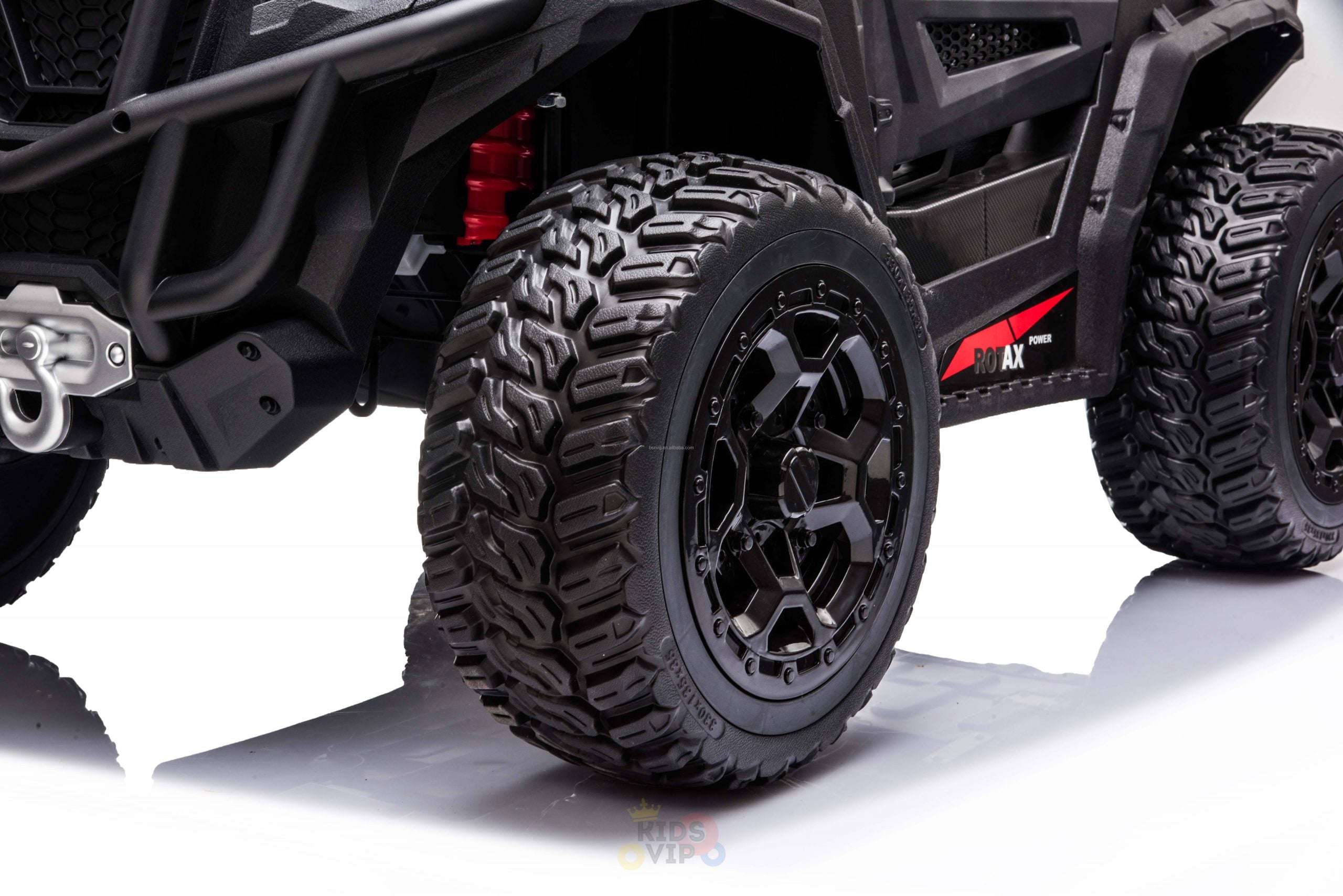 Close-up of an Upgraded 12V Junior Sport Utility Ride On Buggy/UTV 4WD Edition with large, rugged tires on a reflective surface, featuring a sturdy bumper and detailed wheel design, ideal for adventurous young drivers.