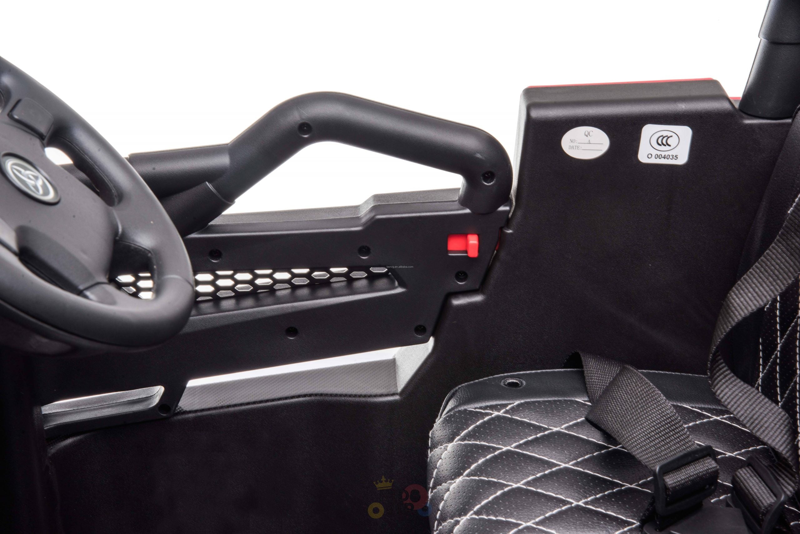 Close-up of the Upgraded 12V Junior Sport Utility Ride On Buggys interior, showcasing a black steering wheel with branding, black seat with white stitching, safety belt, and side handlebar with red button.