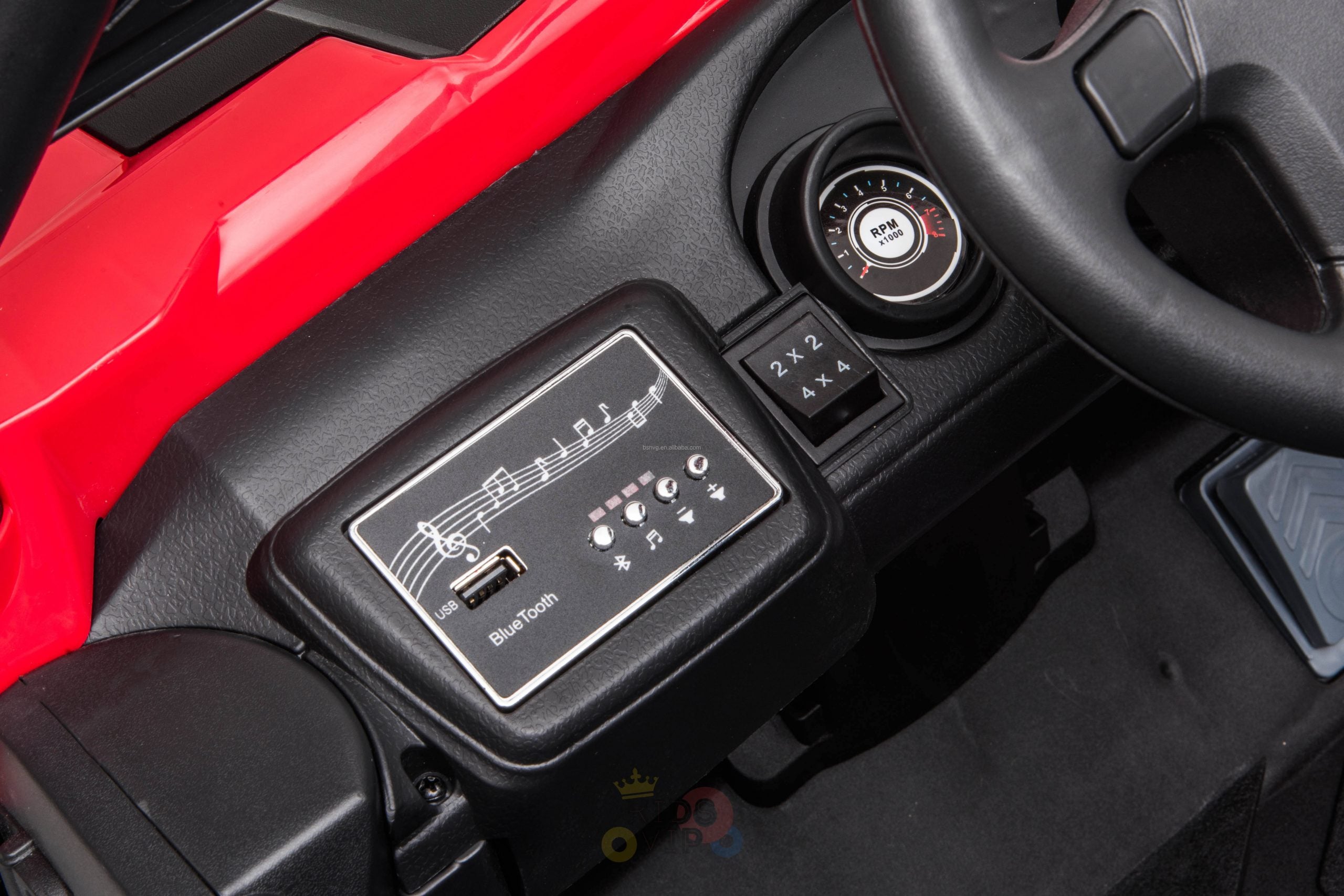Close-up of a car interior showcasing a black Bluetooth audio control panel with musical notes on the dashboard, complemented by a steering wheel and circular air vent with a Push button, reflecting the sleek design of the Upgraded 12V Junior Sport Utility Ride On Buggy/UTV 4WD Edition. The dashboard is red.