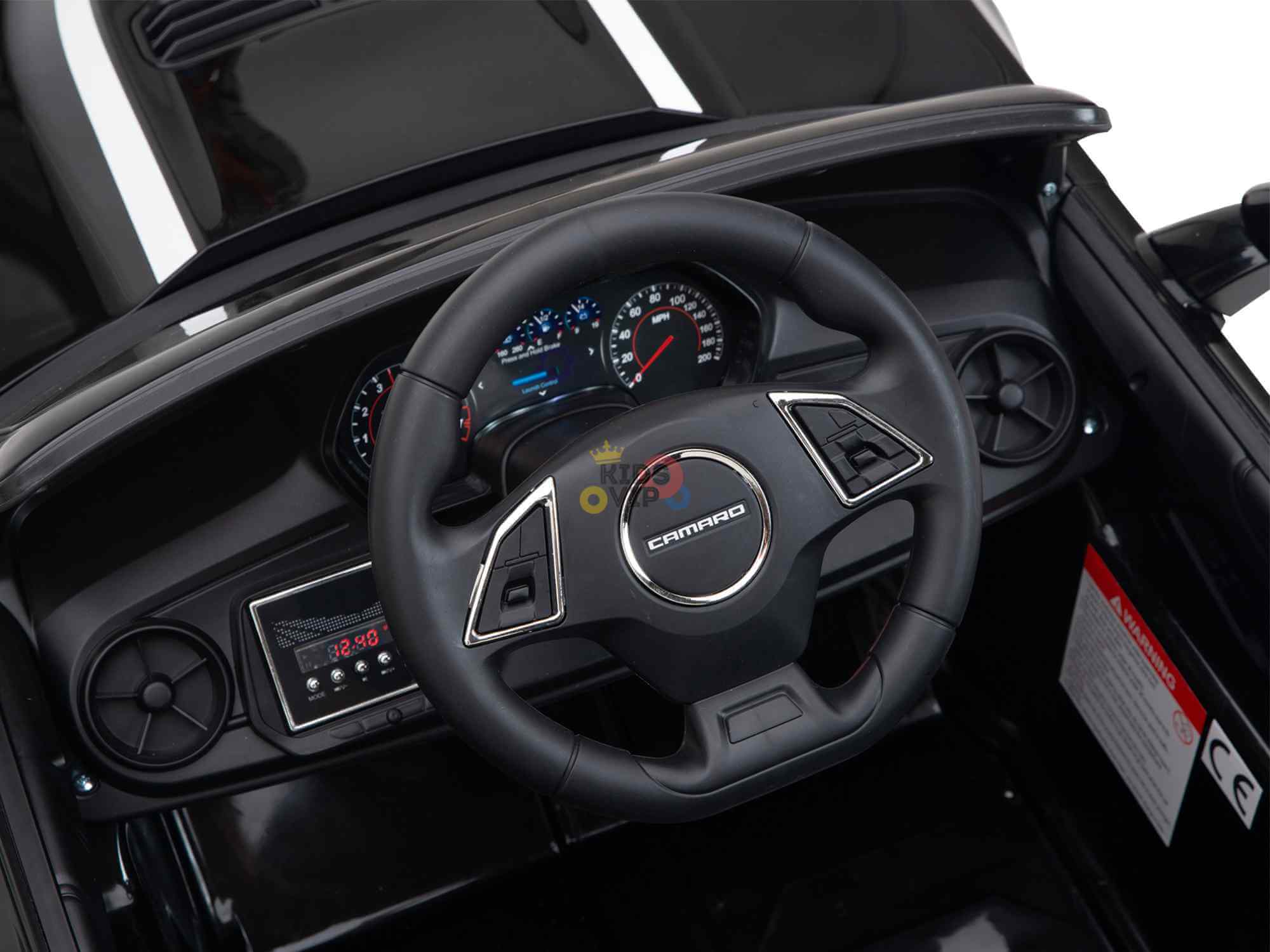 Close-up of the dashboard in a Black Official Sport 12V Chevrolet Camaro Kids and Toddlers Ride on Car, showcasing a Camaro branded steering wheel. The sleek interior features black surfaces, chrome accents, and includes EVA rubber wheels with an ECO leather seat for added comfort.