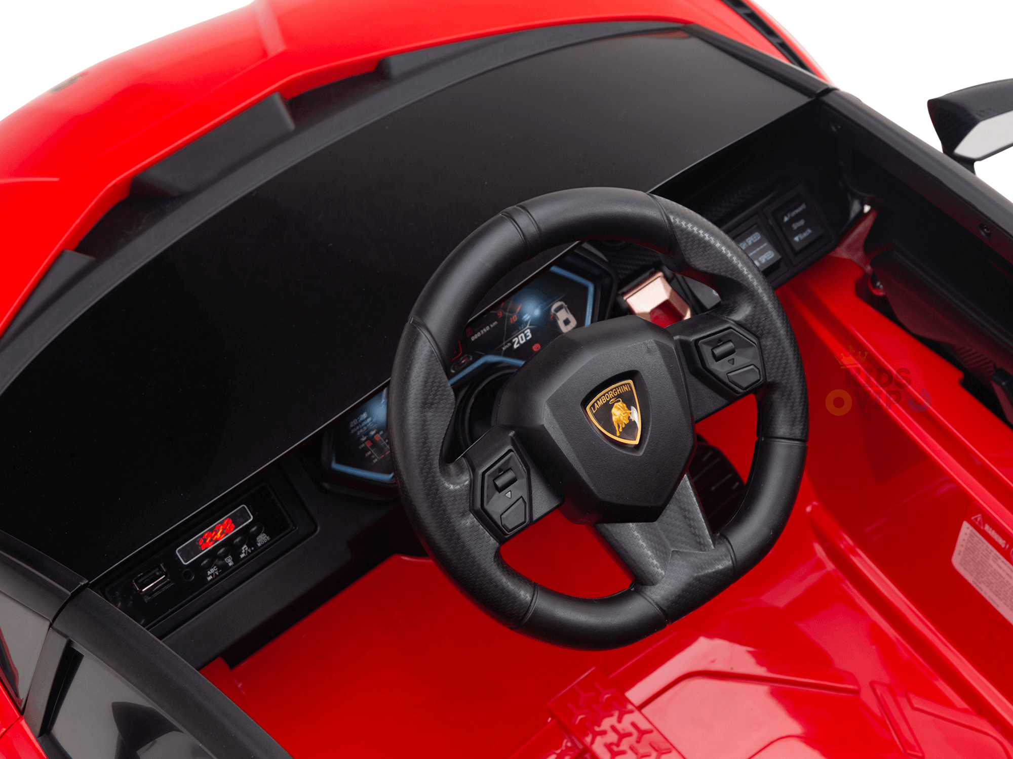 Close-up of the steering wheel on a Red Official 12V Sport Edition Lamborghini Sian Kids and Toddlers Ride On Car, showcasing a central logo. The red and black interior features a button-filled dashboard with a digital screen, replicating sports cars sleek cockpits with butterfly doors.